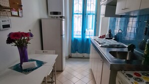 A compact kitchen with a refrigerator, a washing machine, and a sink.