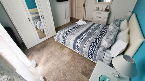 A bedroom with a bed, a TV, a dresser, and a mirror.