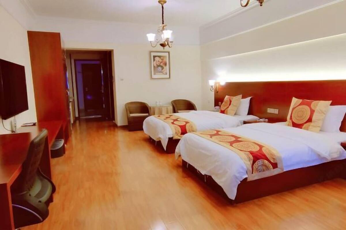 A hotel room with two beds, a TV, a desk, and a chair.