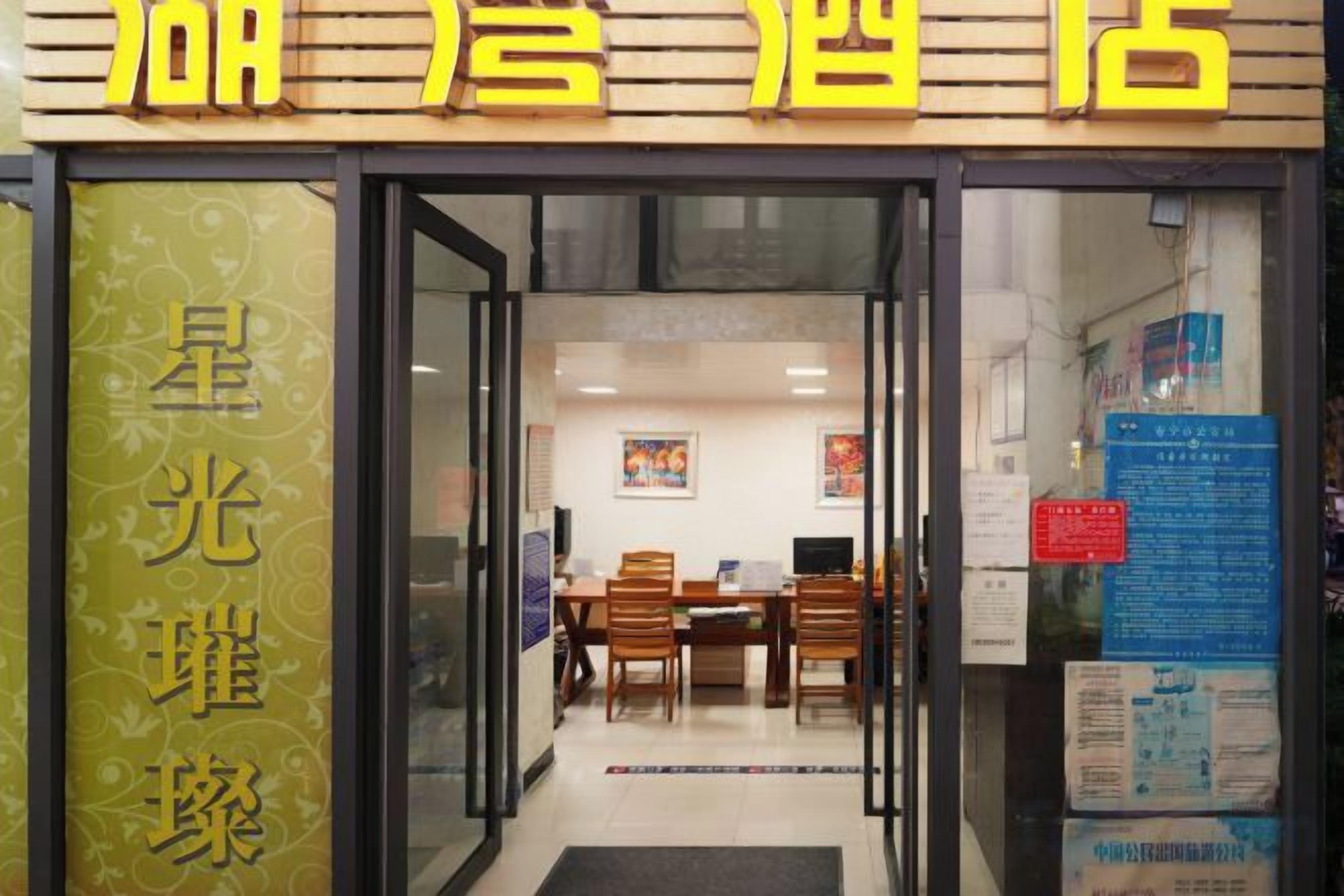 A hotel entrance with a reception desk, a dining area, and a visible menu board.