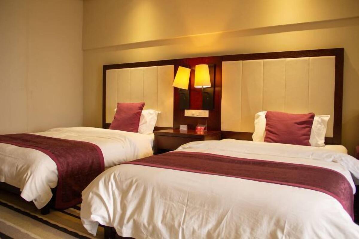 A hotel room with two beds, each with a red and white bedspread, and a large mirror above the beds.