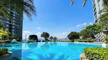 A swimming pool surrounded by greenery and tall buildings.