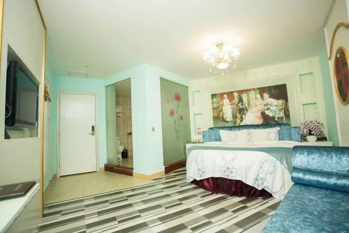 Quarto com cama, sofá, pintura e candelabro.