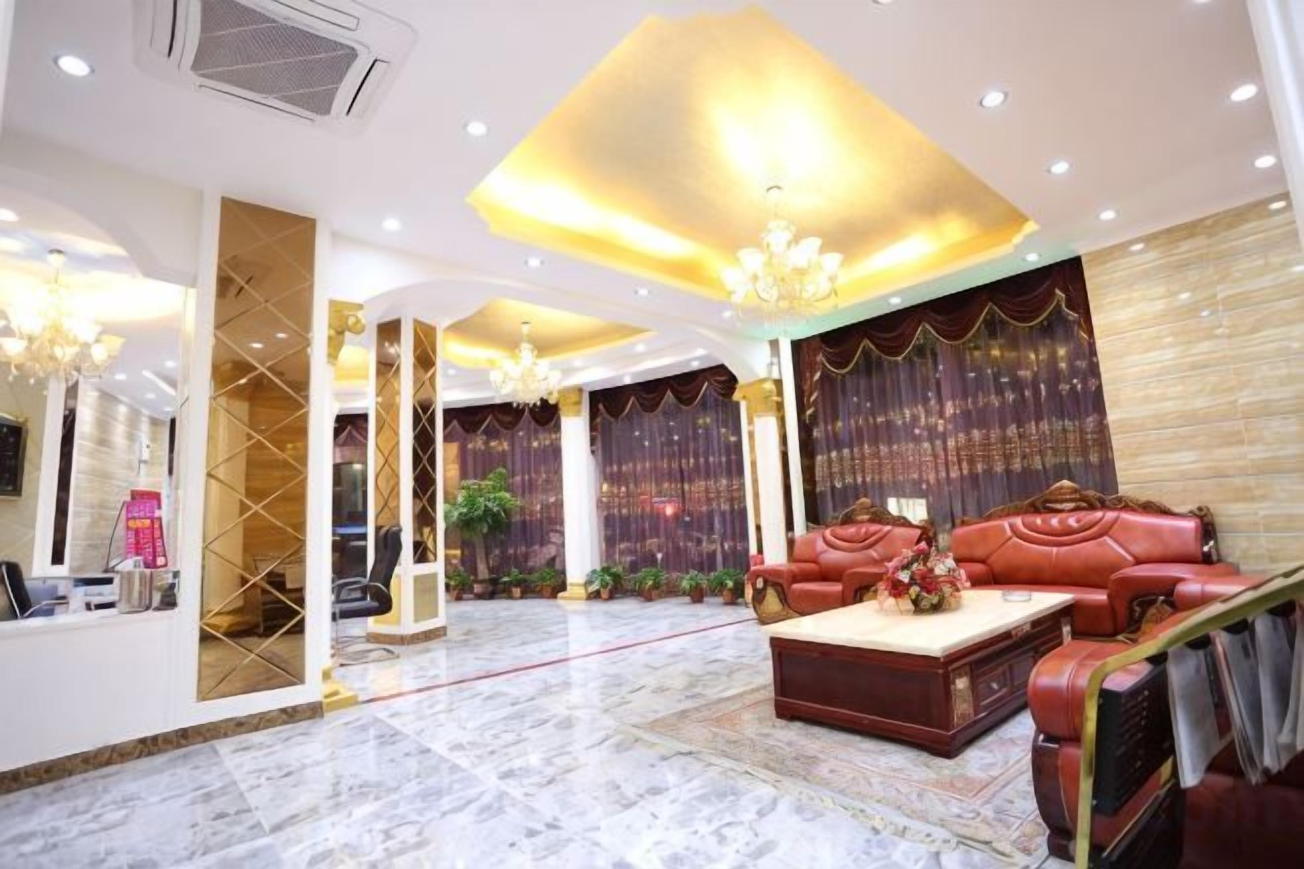 A spacious lobby with a marble floor, a red leather sofa, a coffee table, and a chandelier.