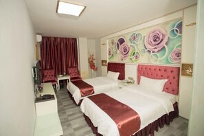 Hotellihuone, jossa on kaksi sänkyä, suuri kukka-aiheinen seinämaalaus ja punainen verho.