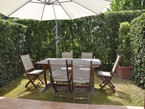 An outdoor patio with a table and chairs, surrounded by dense foliage. - Poolside Stay in Lazise (Lazise)
