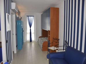 A room with a bunk bed, a blue sofa, a wardrobe, and a mirror.