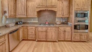 A kitchen with wooden cabinets, a granite countertop, a microwave, and an oven. - Cabin 5 Torreon with Hot Tub (Show Low)