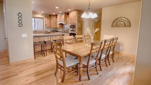 A dining area with a wooden table and chairs, a chandelier, and wooden cabinets in the background. - Cabin 5 Torreon with Hot Tub (Show Low)