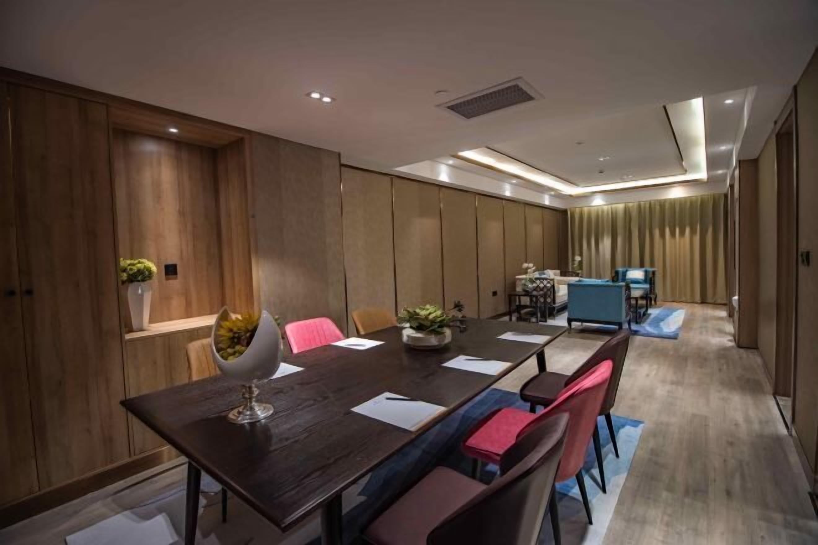 A modern conference room with a long table, several chairs, and a small seating area with a sofa and a coffee table.