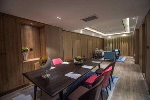 A modern conference room with a long table, several chairs, and a small seating area with a sofa and a coffee table.