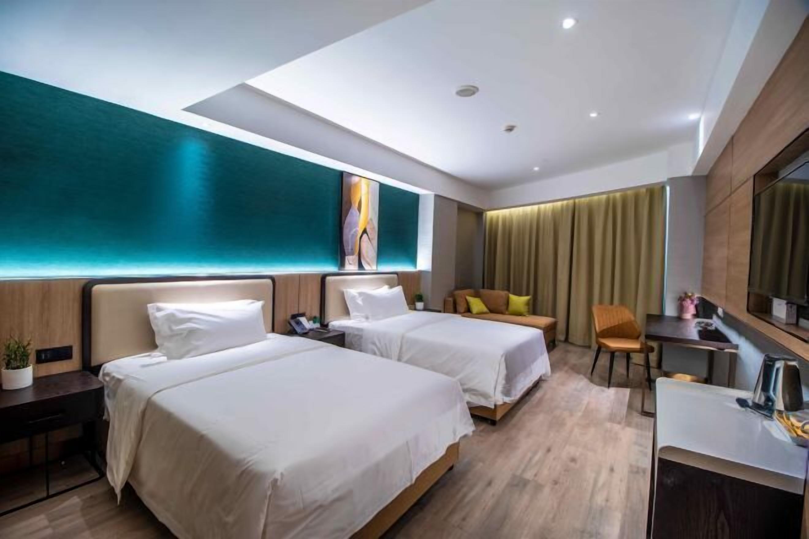 A hotel room with two beds, a desk, a chair, and a large window with curtains.