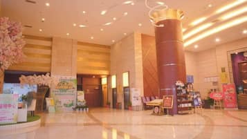 A hotel lobby with a central column, reception area, and various signs and decorations.