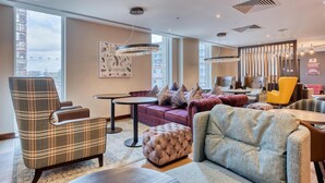 Un espace de détente moderne comprenant un canapé, des fauteuils, un pouf et une table à manger.