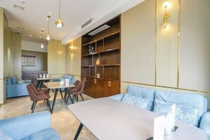 Habitación de hotel con comedor, sofá y estantería.