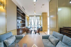 Una habitación de hotel con comedor, un conjunto de sofás y un televisor.