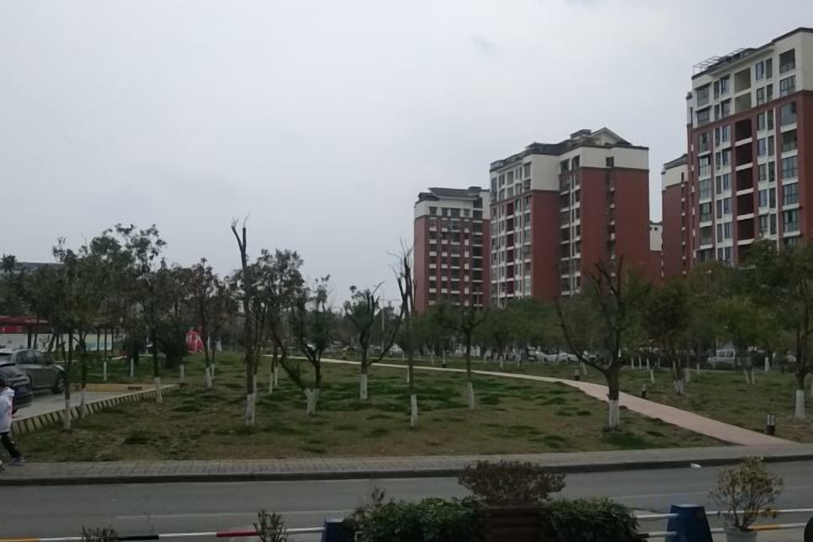 A residential area with multi-story buildings, a paved walkway, and sparse vegetation.