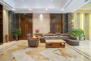 A lobby with a marble floor, a leather sofa, a wooden coffee table, and a potted plant. - Mingwu Jiuzun Hotel (Mianyang)