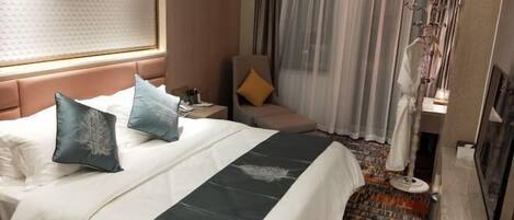 A hotel room with a bed, a nightstand, a chair, a window with curtains, and a floor lamp.