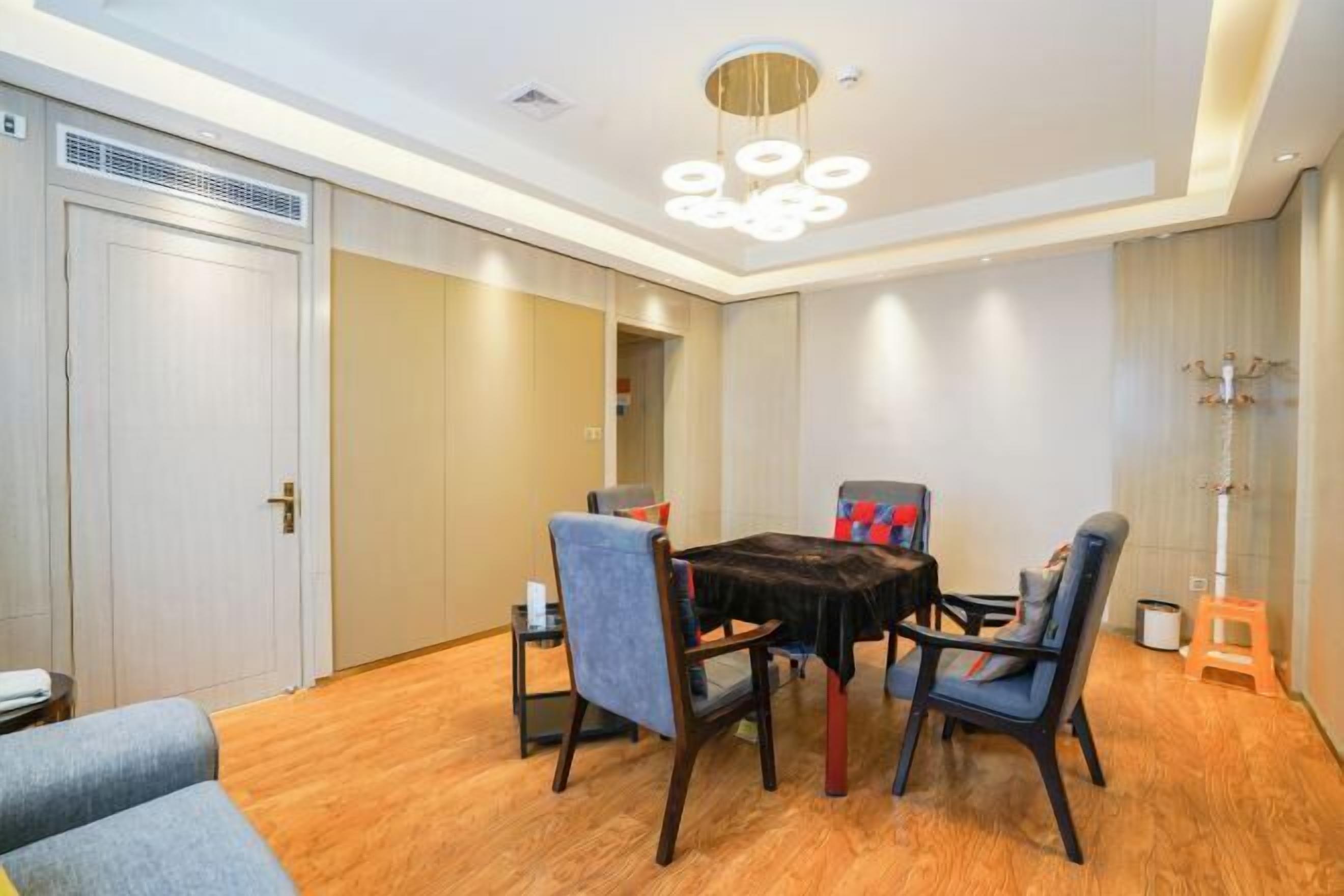 A dining area with a round table, four chairs, and a modern chandelier.