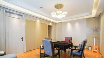 A dining area with a round table, four chairs, and a modern chandelier.