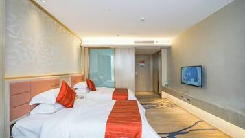 A hotel room with two beds, a TV, and a carpeted floor.