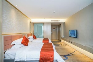 Habitación de hotel con dos camas, televisión y piso alfombrado.