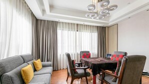 Un salon moderne avec un canapé gris, des coussins jaunes, une table à manger en bois avec des chaises et un lustre.