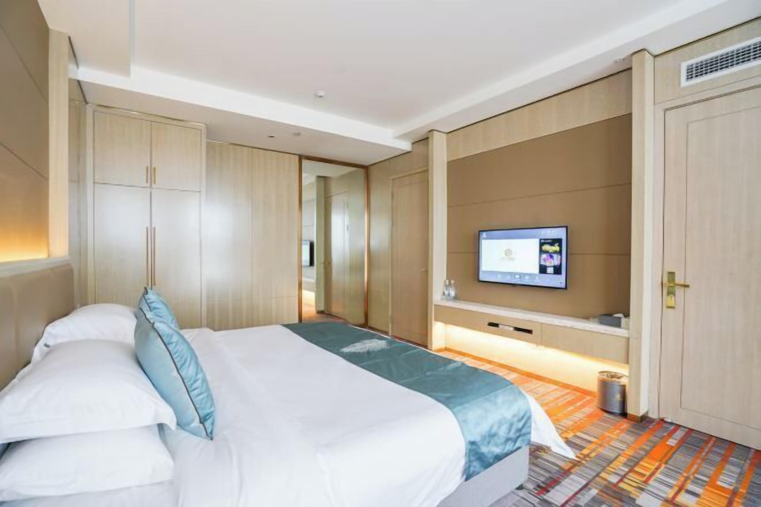 A hotel room with a bed, a TV, and a wardrobe.