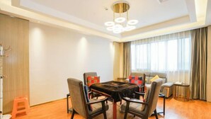 Un salon moderne avec une table ronde, quatre chaises, un canapé et une grande fenêtre avec des rideaux.