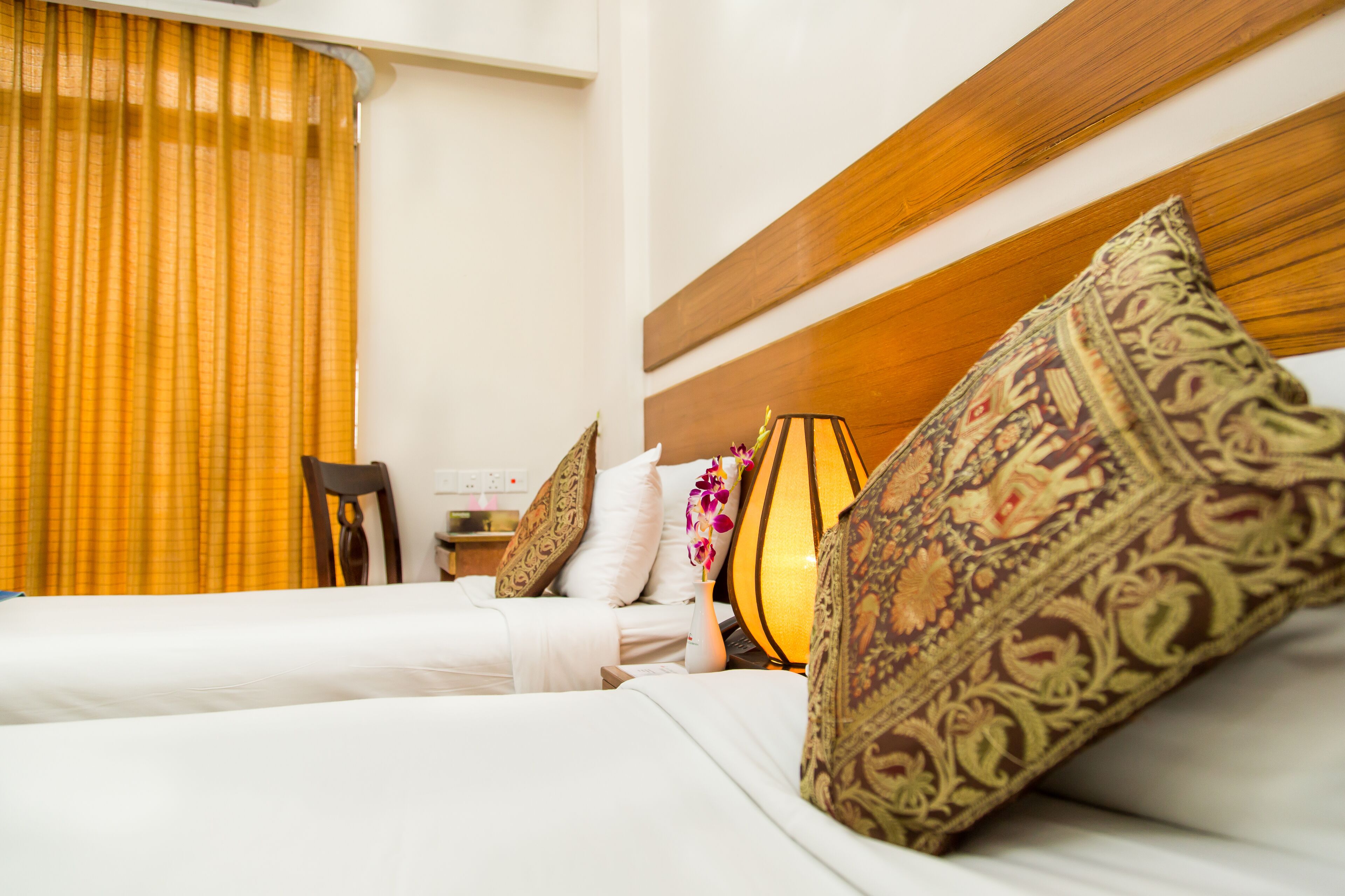 Una habitación de hotel con una cama, almohadas, una lámpara y una silla.