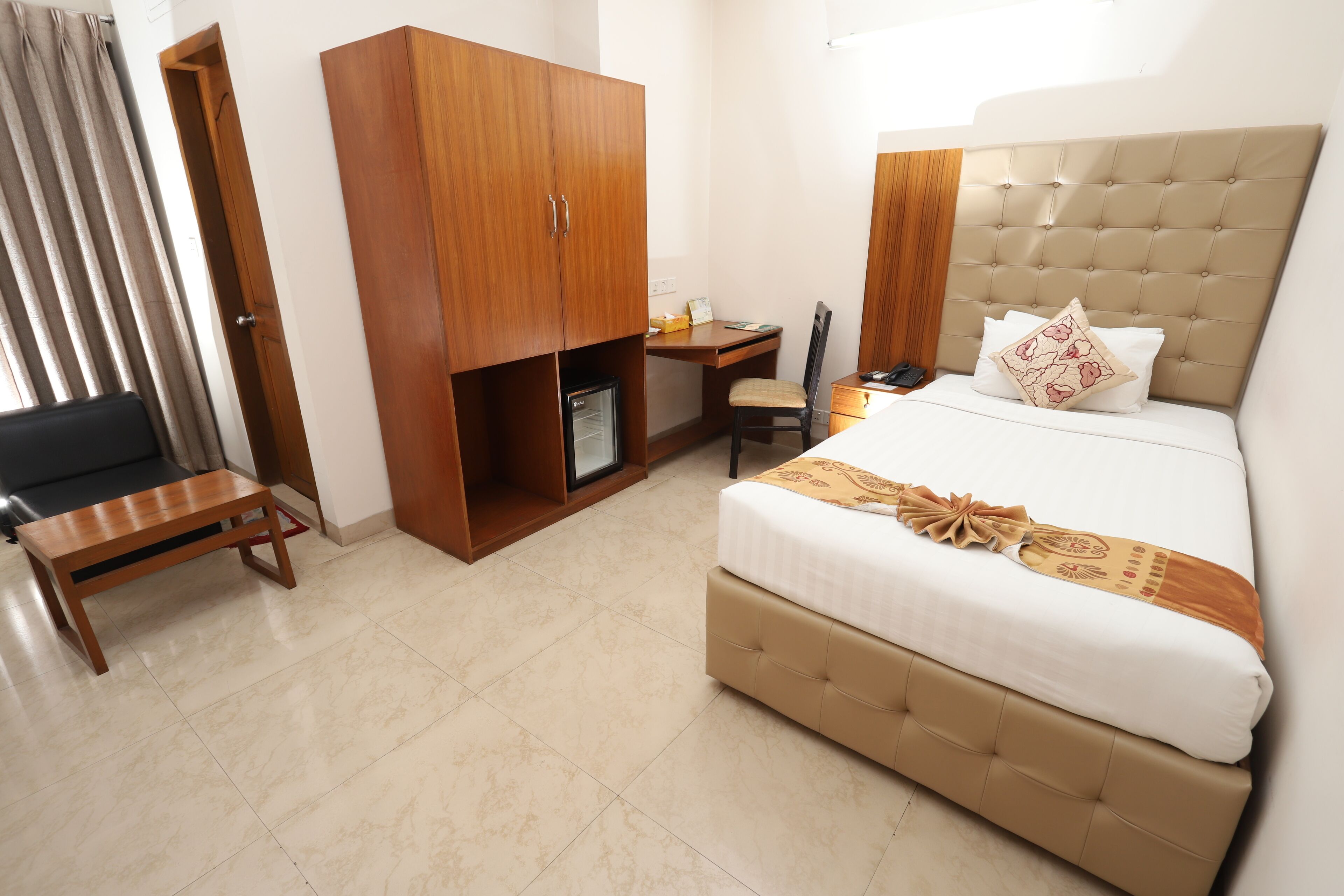 Une chambre d’hôtel comprenant un lit, un bureau, une armoire et un petit coin salon.