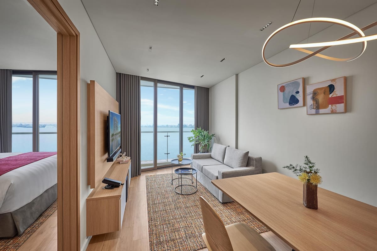 Una habitación de hotel moderna con una cama grande, un sofá, una mesa de comedor y una televisión.