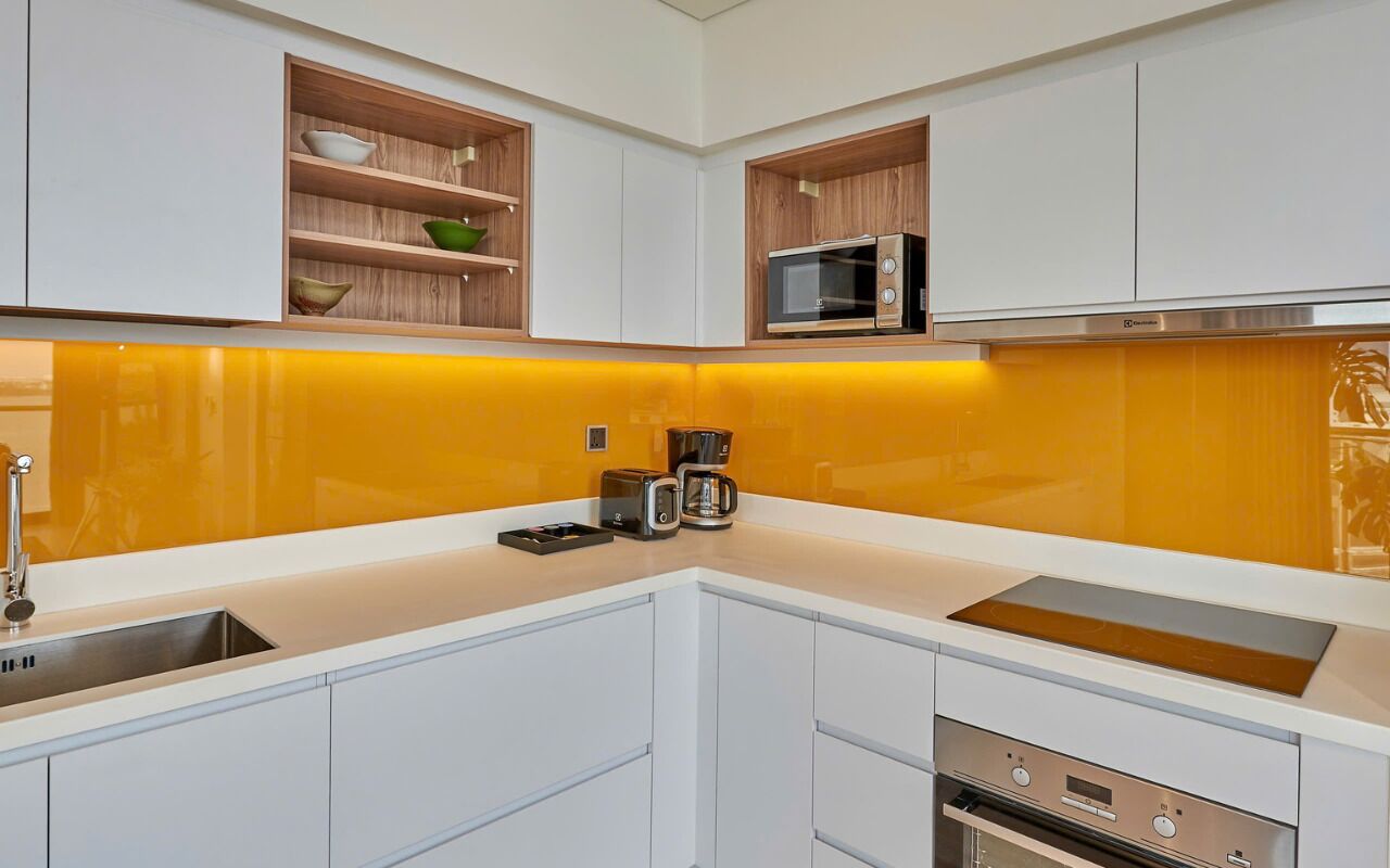 A kitchen with white cabinets, a microwave, a coffee maker, and a built-in oven.