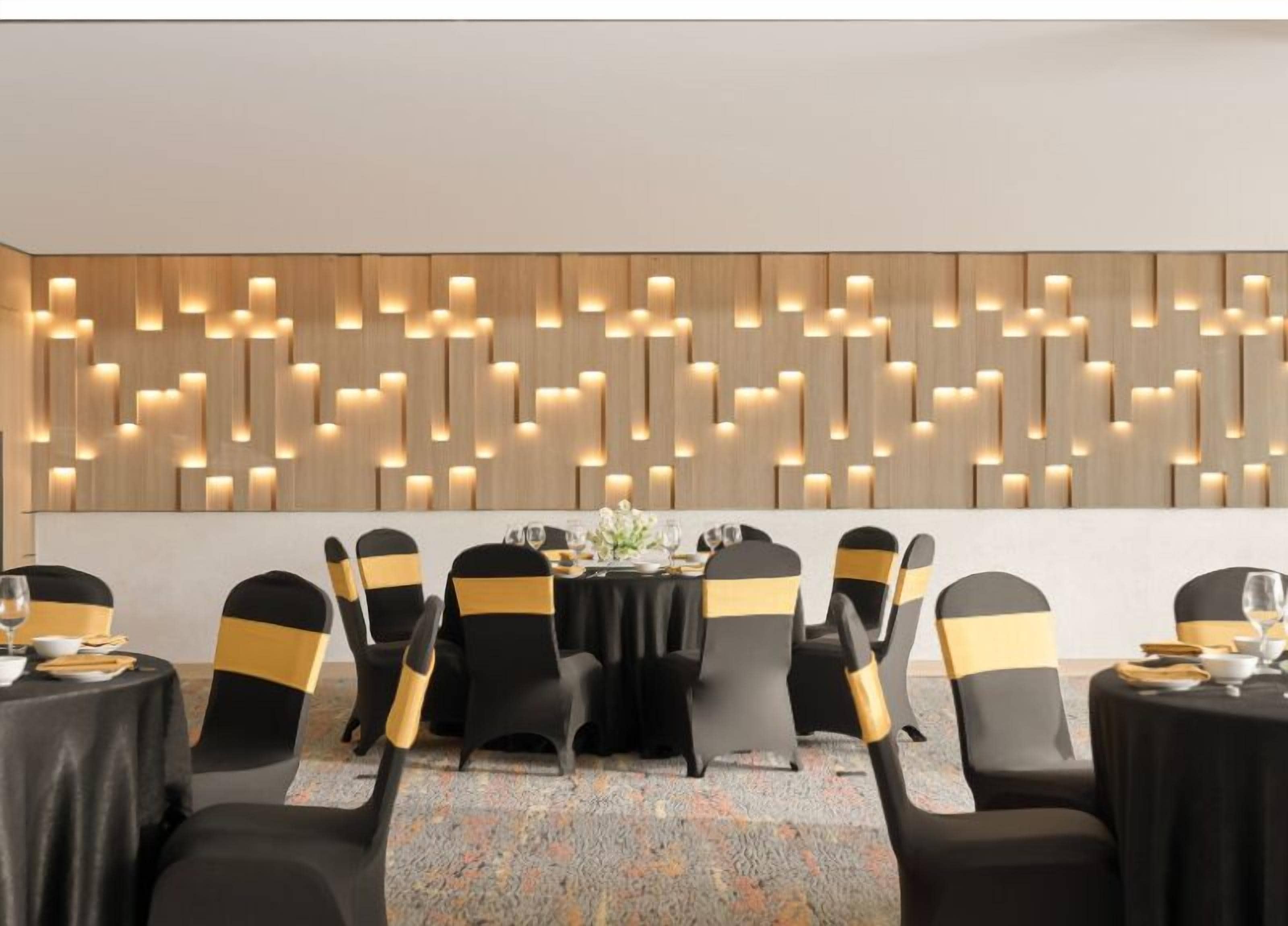 Een vergaderruimte met een modern houten wandpaneel en zwarte stoelen met gouden linten.