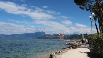 A coastal path with a rocky shoreline, clear water, and distant mountains.