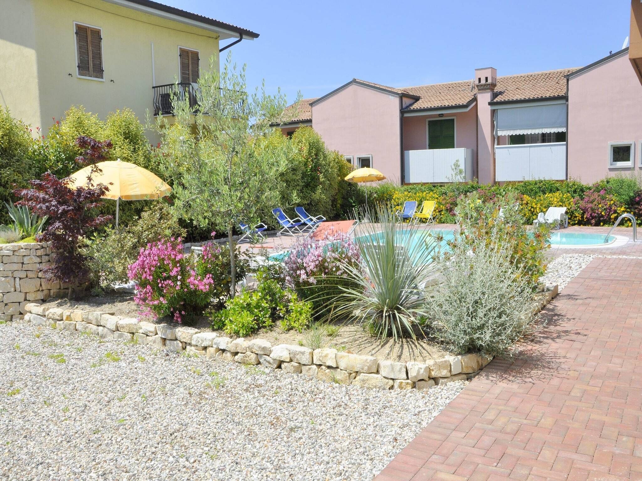 A residential area with a swimming pool, lounge chairs, and a stone pathway.