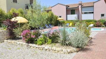 A residential area with a swimming pool, lounge chairs, and a stone pathway.