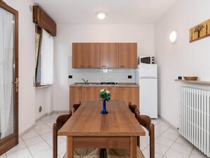 Una cocina moderna con armarios de madera, microondas integrado y una mesa de comedor con sillas.