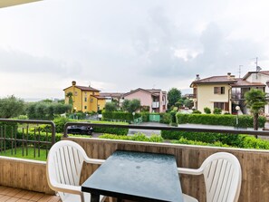 Un balcon avec une table et des chaises, donnant sur un quartier résidentiel avec des maisons aux couleurs vives et de la verdure.
