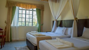 A hotel room with two beds, a window with curtains, a bedside table, and a chair. - Kabarak University Guesthouse (Eldama Ravine)