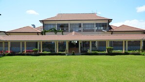 A two-story building with a covered patio area and a well-maintained lawn. - Kabarak University Guesthouse (Eldama Ravine)
