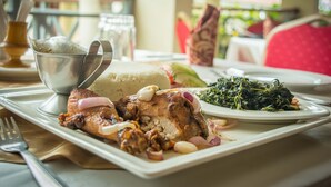 A dining table with a plate of food, including a piece of meat, greens, and a bowl of soup. - Kabarak University Guesthouse (Eldama Ravine)