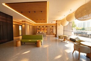 A modern lobby with a green sofa, wooden accents, and a view of the city. - JI Hotel (Huai'an Bochishan Park) (Huai'an)