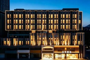 A multi-story hotel with a modern facade, illuminated windows, and a ground-level entrance with signage. - JI Hotel (Huai'an Bochishan Park) (Huai'an)