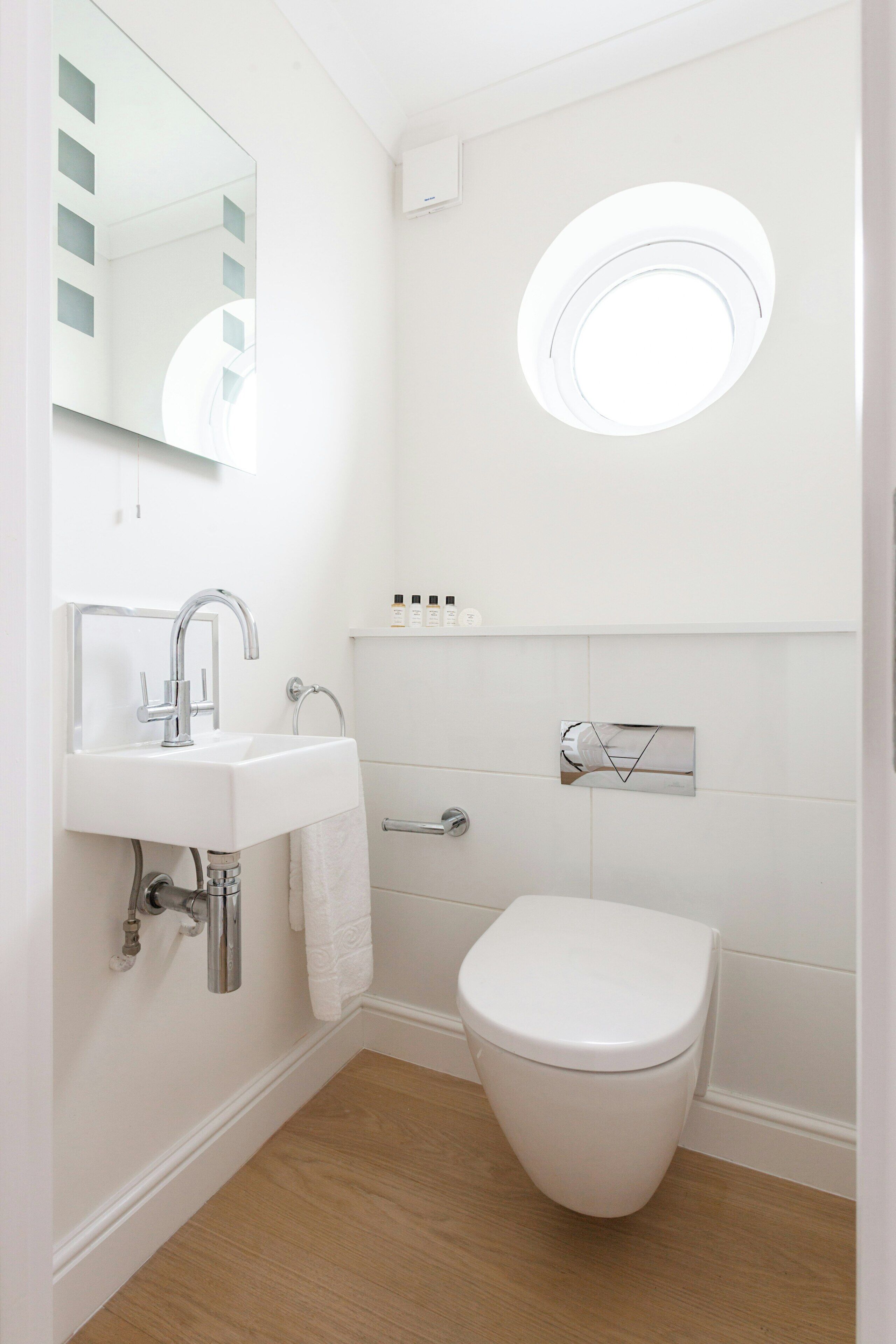 Un baño moderno con un lavamanos blanco, un inodoro y un espejo.