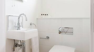 Un baño moderno con un lavamanos blanco, un inodoro y un espejo.