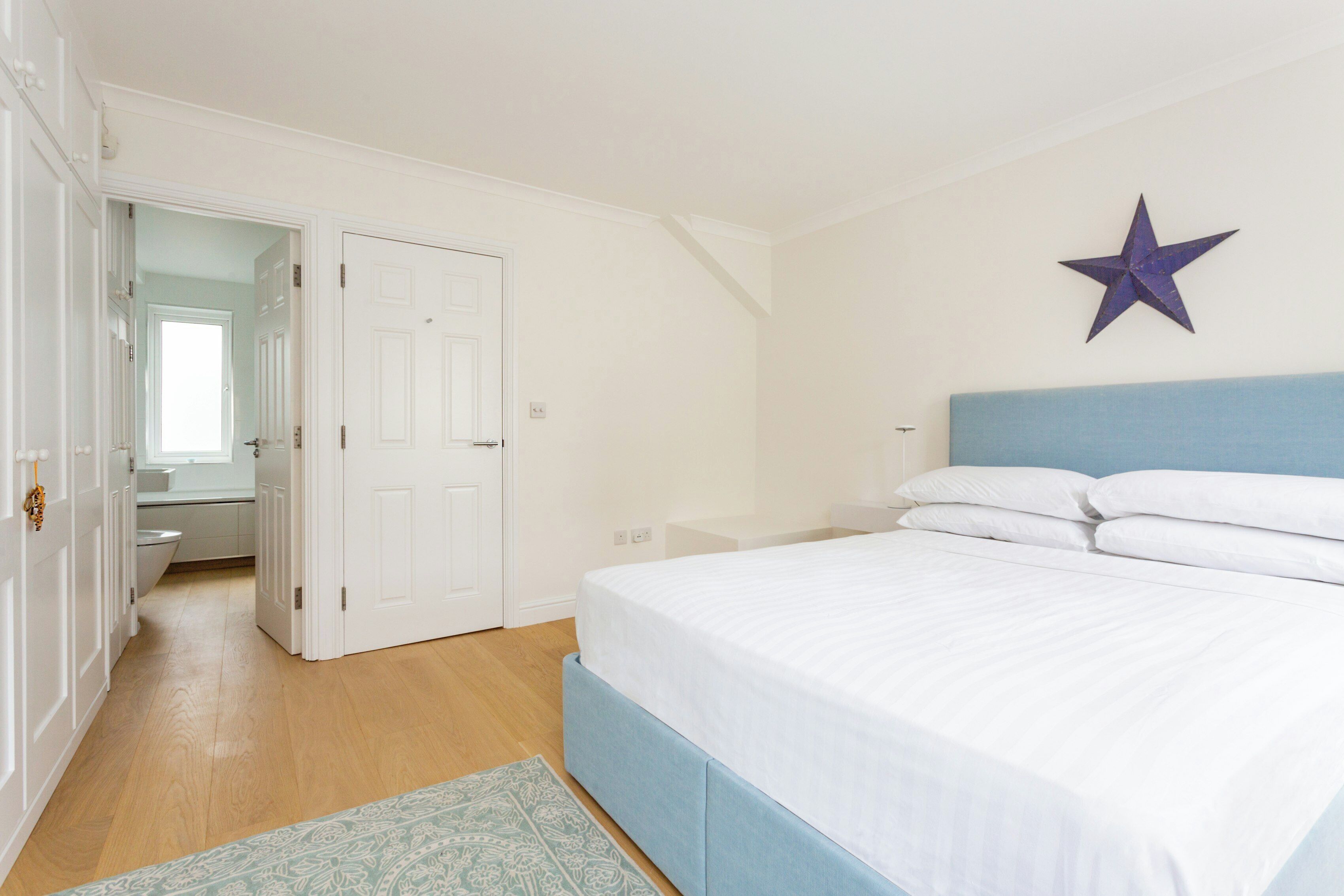 A bedroom with a bed, a star decoration on the wall, and a bathroom visible through an open door.