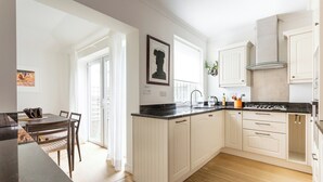 A modern kitchen with white cabinetry, a black countertop, and a dining area with a table and chairs.