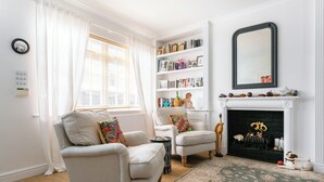 A living room with two armchairs, a bookshelf, a fireplace, and a mirror.